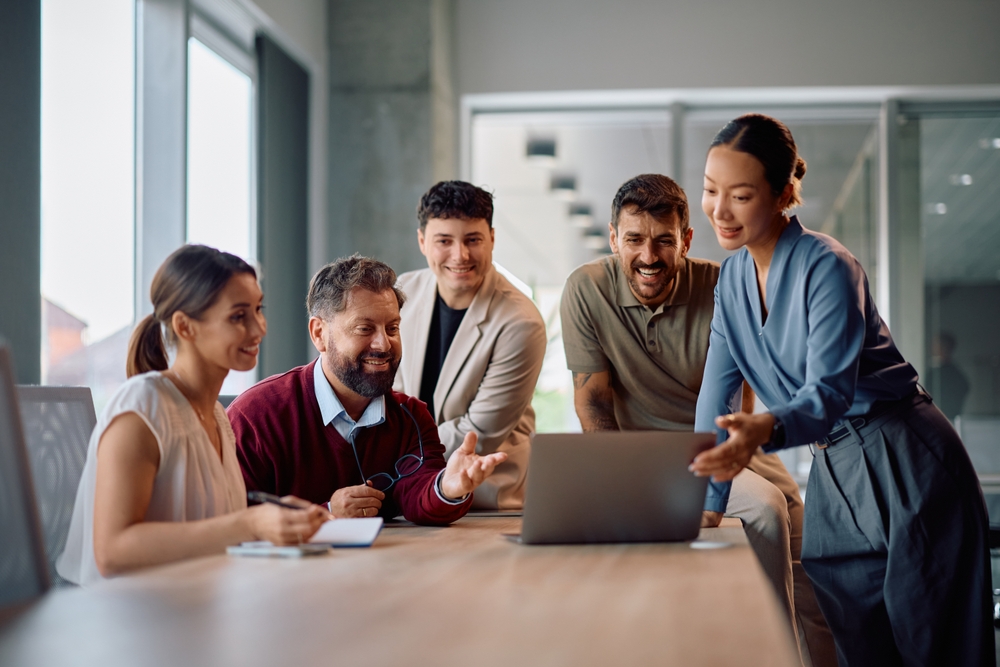 team collaborates around shared laptop.